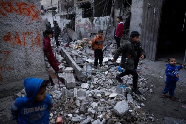 Children are seen walking in an urban area with co<em></em>ncrete debris on the ground.