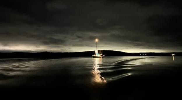 A sailboat lit up at night, including a bright star on the top of the mast.