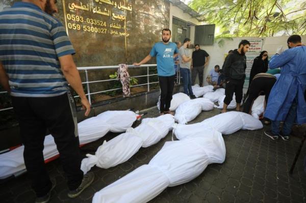 People stand around wrapped bodies