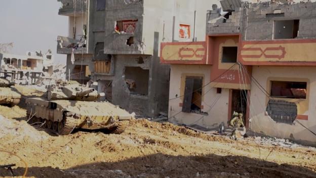 A tank is shown beside a heavily damaged co<em></em>ncrete building.