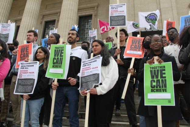 Students are seen holding protest signs reading 'Together we can achieve' during an outdoor demonstration.