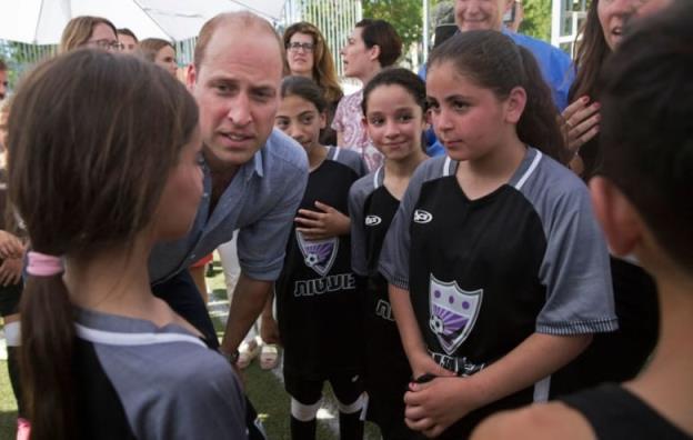 An adult leans down to speak with children.