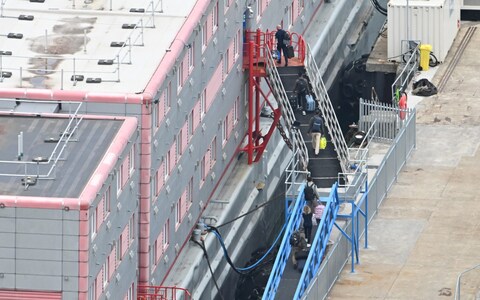People carrying bags are seen walking up the ramp into the the Bibby Stockholm accommodation barge on Mo<em></em>nday 
