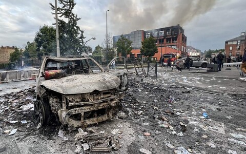 A car burnt in riots over teenager's murder