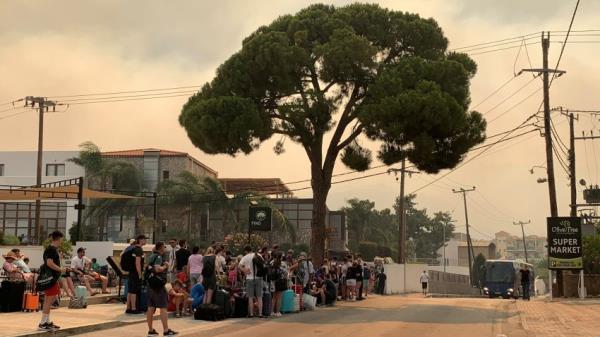 Tourists are being evacuated as wildfire burns near Lindos, on the island of Rhodes, Greece, July 22, 2023.