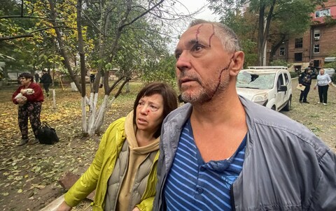 Injured residents look at the damage caused by a Russian missile strike to their apartment building in Kharkiv
