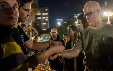 Volunteers tie yellow ribbons on demo<em></em>nstrators in Tel Aviv at a rally to demand that Mr Netanyahu secures the release of the hostages