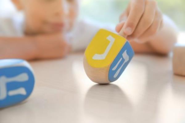 Jewish boy playing with dreidel at home