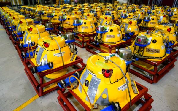Approximately 50 large yellow devices, roughly spherical, with bright blue attachments, inside red square me<em></em>tal f<em></em>rames lined up.