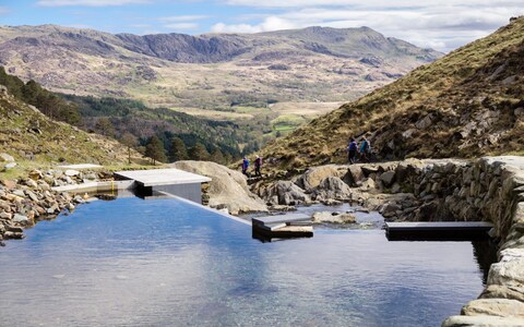Hikers pass a micro hydro-electric plant on the Afon Llan river in Snowdo<em></em>nia Natio<em></em>nal Park