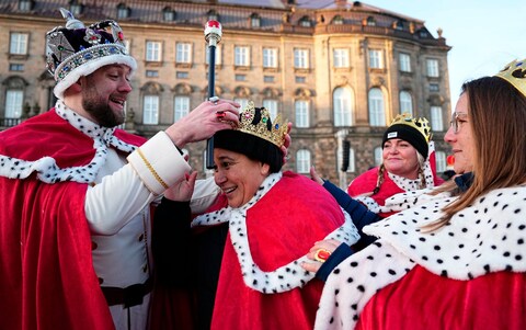 People wearing royal costumes and crowns  gather at Christiansborg Castle Square in Copenhagen