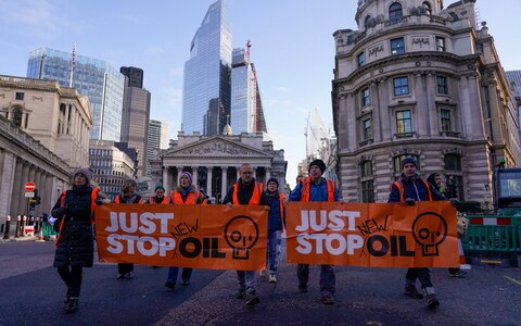Just Stop Oil activists with banners slowing traffic in the financial district of the City of Lo<em></em>ndon in December 2023