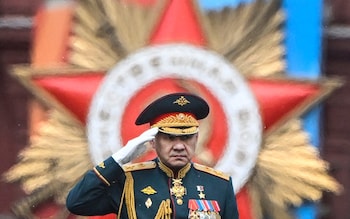 A tank soldier salutes from the top of a green-painted gun turret