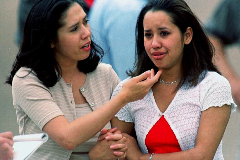FILE - Kathy Zamora, left, comforts her friend Christine Medina, a sophomore at Columbine High School, after she escaped from the school when two gunmen entered the facility and went on a shooting rampage Tuesday, April 20, 1999, in the southwest Denver suburb of Littleton, Colo. (AP Photo/David Zalubowski, File)