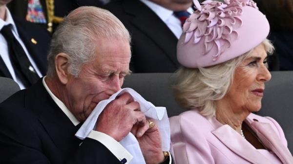 King Charles reacts next to Queen Camilla as they attend a commemorative event for the 80th anniversary of D-Day.</p>
<p> Pic: Reuters