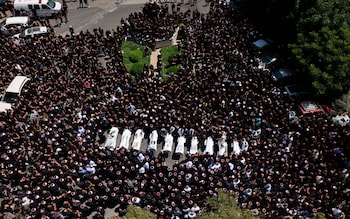 Mourners surround the coffins of 10 of the 12 people killed in a rocket strike from Lebanon in a mass funeral on Sunday