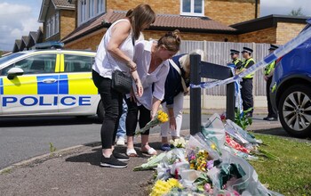 Friends of the Hunt family leave flowers near their home in Bushey the day after the attack
