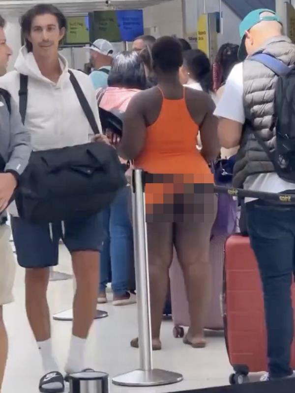 A woman was seen with her orange halter top dress hiked up, exposing her lower cheeks.