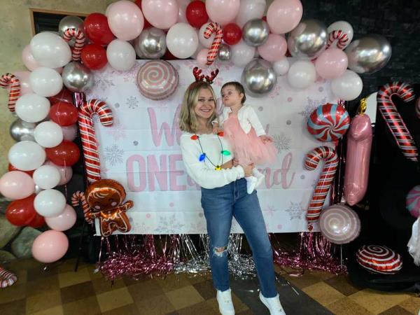 Iris is pictured with her mother at her first birthday party in front of a winter 'one'-derland backdrop. 