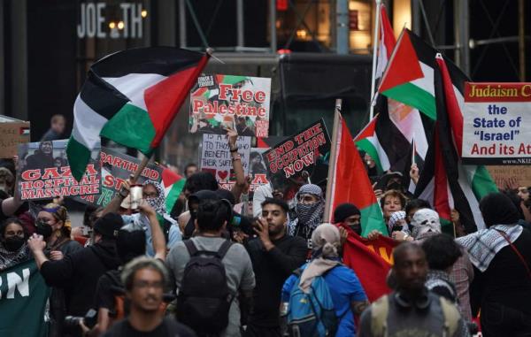 A group of a few dozen pro-Palestinian protesters at a rally in Manhattan wave signs and Palestinian flags.