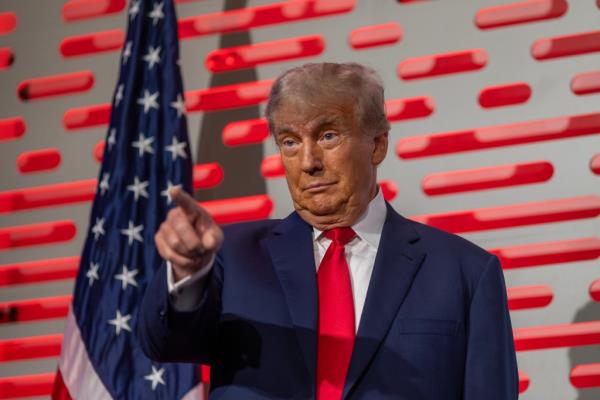 Do<em></em>nald Trump stands on stage pointing a finger at the audience. 