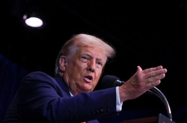 Trump speaks into a microphone with his hand in the air. 