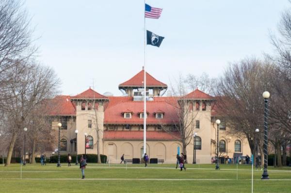 Exterior of Queens College building with a flagpole outside.