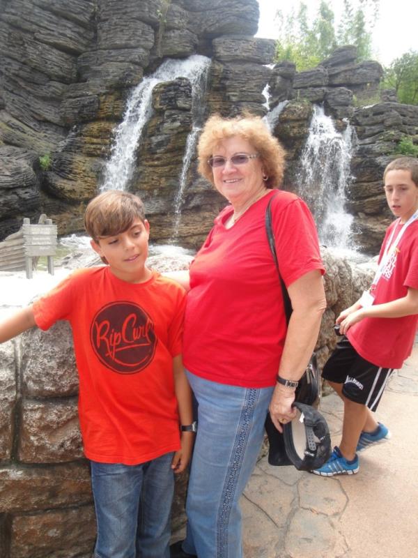 Young Omer Wenkert and grandmother Tsili standing in front of a water feature at Disney World