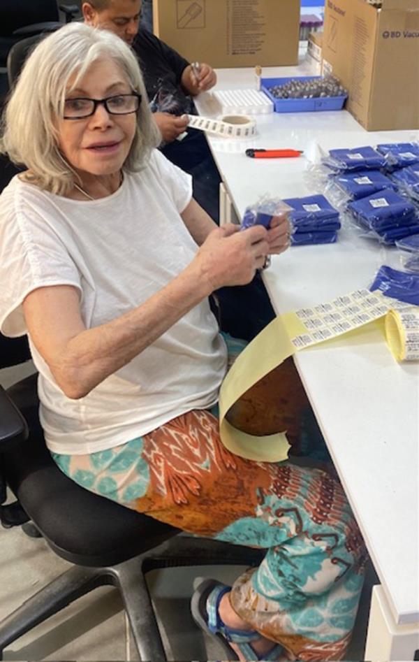 Lucy Lipiner sitting at a work table surrounded by packing supplies