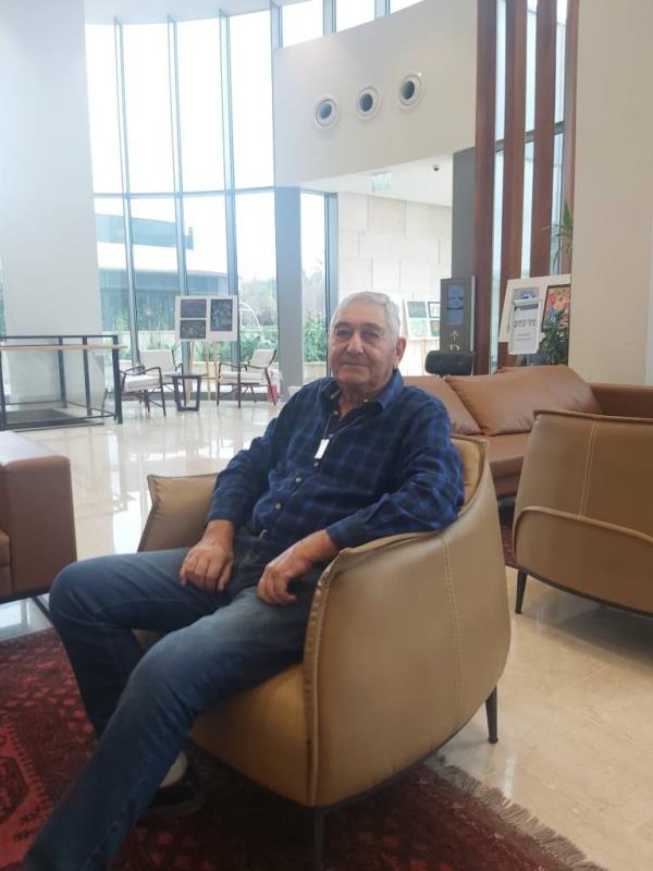 Yaakov Weissmann sitting in a chair in a building lobby wit large windows behind him