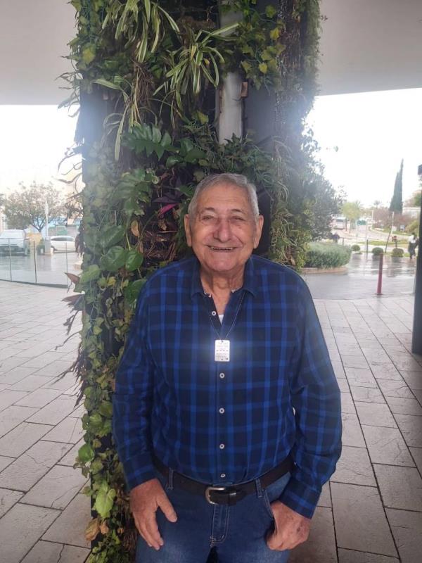 Yaakov Weisman standing outside in front of greenery