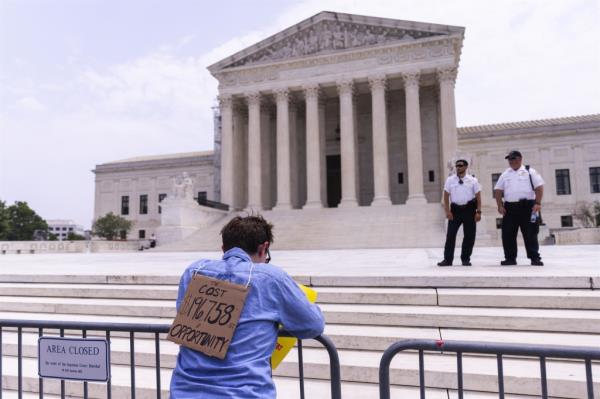 Supporters of student loan forgiveness check for news on United States Supreme Court decisions outside the Supreme Court in Washington, DC.