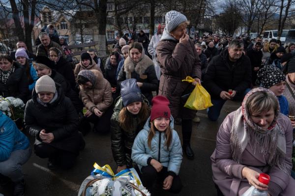 Ukrainian civilians cry at a memorial.