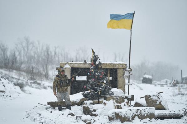 A Ukrainian soldier stands near an improvised Christmas tree on the front. 