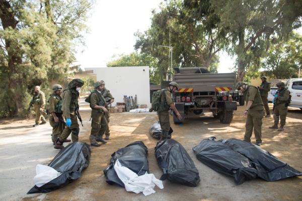 Israeli soldiers remove the bodies of civilians, who were killed days earlier in an attack by Palestinian militants on this kibbutz near the border with Gaza, on Oct. 10, 2023 in Kfar Gaza, Israel.