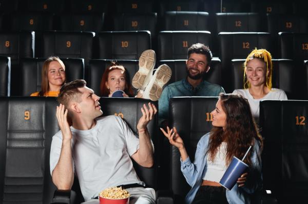 Young rude, drunk men holding his feet on the seat while watching movie at the cinema. close up photo. 