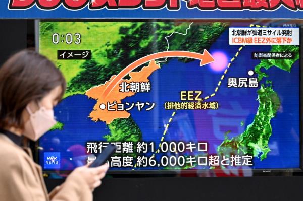 A pedestrian walks past a television screen broadcasting a news report on a North Korean missile launch in Tokyo on Dec. 18, 2023. 