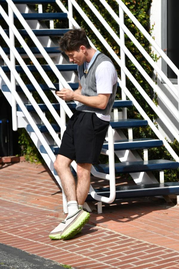 Barry Keoghan exiting a meeting on Melrose Avenue, Los Angeles, while looking at his phone, styled in an outfit embodying the 'wrong shoe theory'