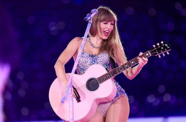Taylor Swift singing o<em></em>nstage with a guitar. 