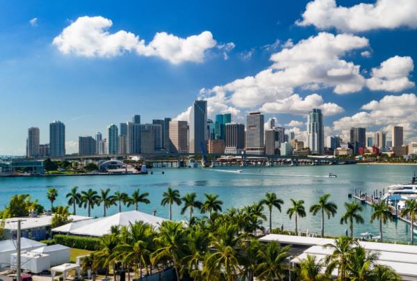 Downtown Miami skyline with palm trees and Biscayne Bay in the foreground.