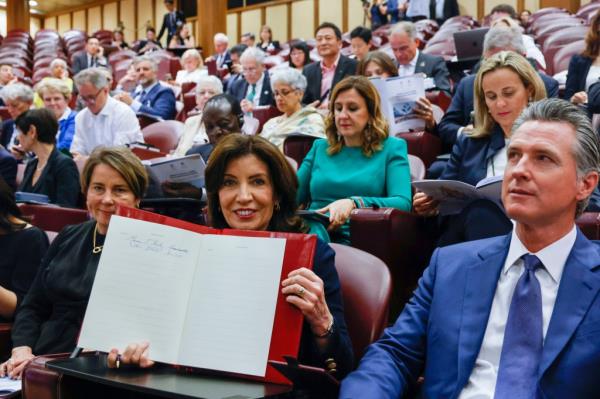 Governors Kathy Hochul, Maura Healey, and Gavin Newsom sitting in the Synod Hall at the Vatican City for a climate change discussion.