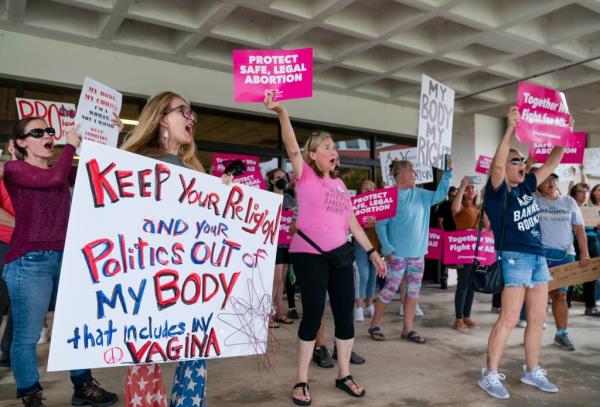Protesters carry signs and listen to speakers as they demo<em></em>nstrate in front of the Paul G. Rogers Federal Building and U.S. Courthouse on May 3, 2022, in West Palm Beach, Florida.