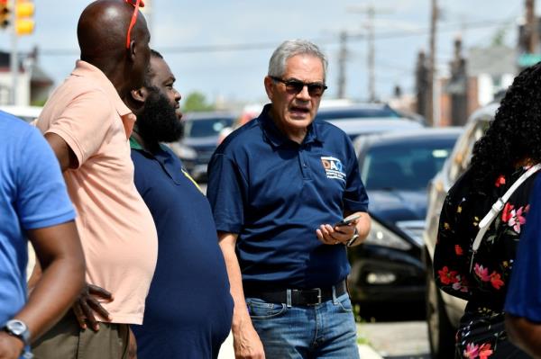 Philadelphia DA Larry Krasner talks with community members near the scene of Monday's mass shooting that killed five.