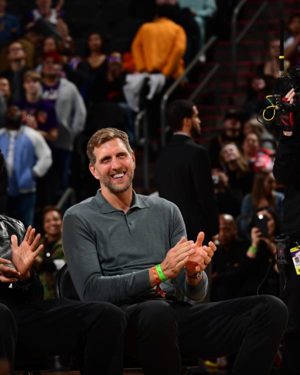 Dirk Nowitzki sitting on the floor with his hands up at Shawn Marion's Ring of Ho<em></em>nor ceremony in Phoenix, Arizona.
