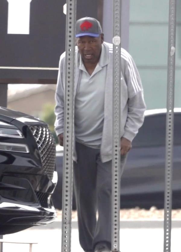 Simpson, 76, hobbled along the street wearing a grey polo shirt with a matching tracksuit jacket and sweatpants and do<em></em>nned a blue and white ba<em></em>seball cap while holding his electro<em></em>nic device safely in his arm. 