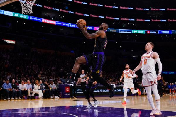 LeBron James (23), front left, lays up the ball as New York Knicks guard Do<em></em>nte DiVincenzo (0) watches during the first half.