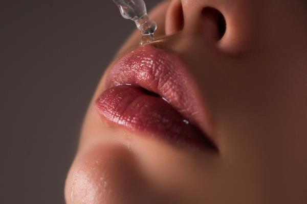 Close-up of a woman's lips being treated with hyaluro<em></em>nic acid and lip oil for lip care