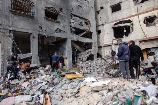 Palestinians search for missing people under the rubble of destroyed buildings following Israeli air strikes, in Khan Yunis, southern Gaza Strip, 12 January 2024. 