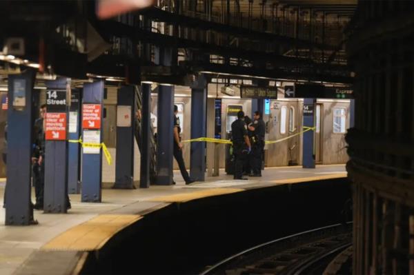 Police officers stand near crime scene tape wher<em></em>e a train is stopped at the 14th Street/Unio<em></em>n Square subway platform. 