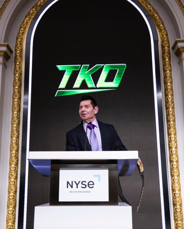 Vince McMahon stands at a podium during a ceremony with Dwayne 